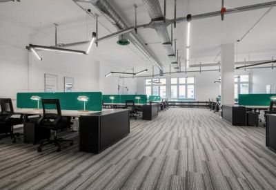 Bright open-plan workspace featuring black desks with teal privacy dividers and ergonomic chairs.
