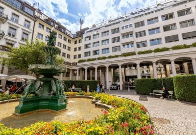 Elegant stone fountain surrounded by yellow flowers in a quiet building courtyard.