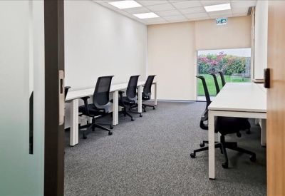 Private office with white desks, black chairs, and a large window showing green landscape.