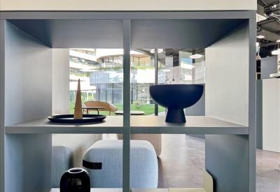 Close-up of a grey shelving unit decorated with a blue bowl and a black vase in a bright room.