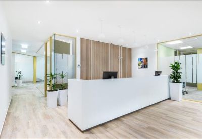 Clean white reception desk in a bright lobby with wood paneling and indoor plants.