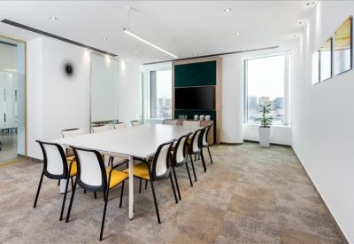 Spacious boardroom featuring a long white table, yellow-backed chairs, and a large monitor.