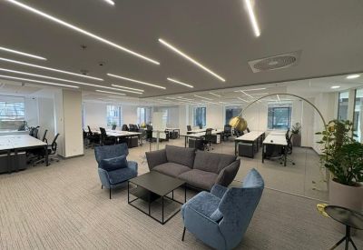 Large open-plan coworking space with blue armchairs and a grey sofa lounge area.