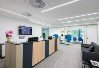 Modern reception desk with wood paneling, blue chairs, and a floral arrangement.
