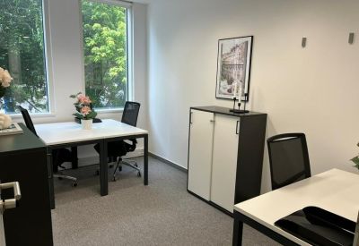 Bright two-person office suite with white desks and black mesh chairs.