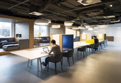Long communal workspace with integrated desk lamps and industrial-style ceiling.