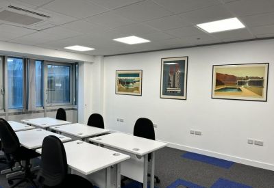 Modern classroom-style office space with white desks and framed wall art.
