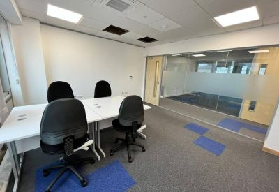 Bright four-person private office suite with glass partitioning and blue carpet accents.