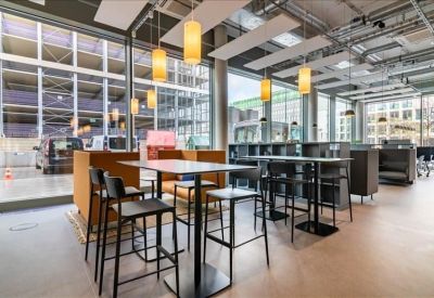 Spacious communal dining area with high tables, bar stools, and industrial ceilings.