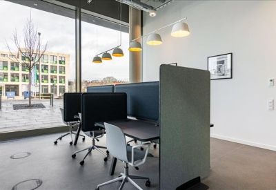 Modern coworking area with partitioned desks and floor-to-ceiling windows.