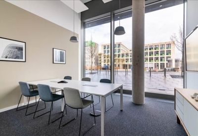Bright conference room with a white table, grey chairs, and a large window.