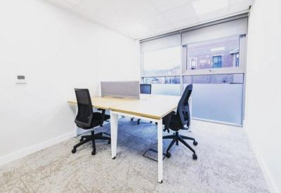 Bright white private office with four desks and minimalist furnishings.