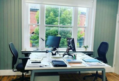 Modern workspace with wood flooring and green wood-paneled feature walls.