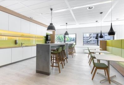 Modern communal kitchen and dining area with yellow backsplash and industrial lighting.