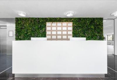 Minimalist reception desk backed by a lush green living plant wall.