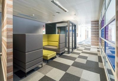 Breakout space with modular grey and yellow seating and checkered carpet.