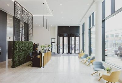 Bright reception area with a green plant wall and blue lounge seating.