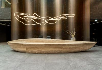 Sleek wooden boat-shaped reception desk against a vertical slat feature wall.