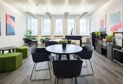 Vibrant communal breakout area with green ottomans, a foosball table, and colorful wall art.