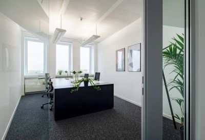 Private office suite with a dark desk and large windows offering natural light.