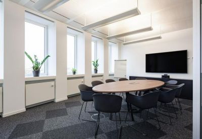 Contemporary meeting room with an oval table and a large wall-mounted monitor.