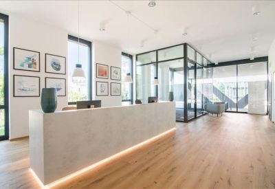 Bright reception area with a minimalist stone desk, wooden flooring, and framed wall art.