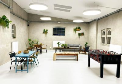Spacious communal breakout room with a foosball table, lounge seating, and potted plants.