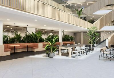Spacious communal dining area with indoor plants and tiered wooden balconies.