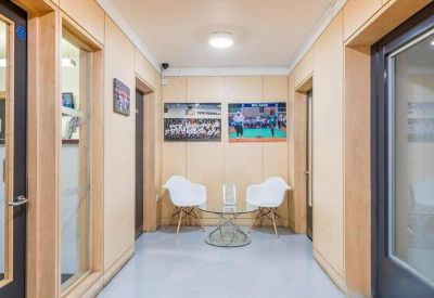 Modern reception hallway featuring wooden wall panels and a glass coffee table with white chairs.