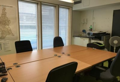 Professional meeting room with a large wooden table, black ergonomic chairs, and bright windows.