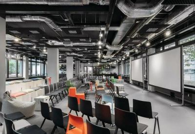 Spacious communal event space with rows of chairs and presentation screens.