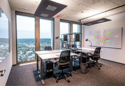 Modern open-plan office with sit-stand desks and expansive city views.