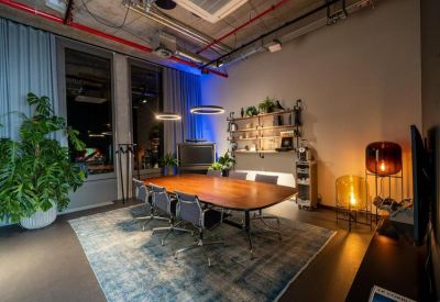 Sophisticated meeting room with a wooden table, blue rug, and warm ambient lighting.