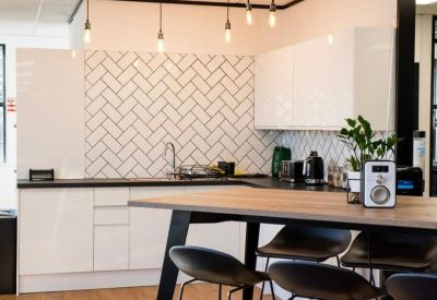 Modern kitchen area with white herringbone backsplash and a wood-topped breakfast bar.