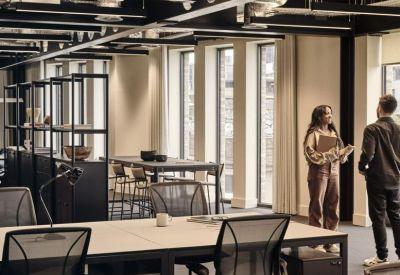 Open-plan office with black industrial ceilings, white desks, and ergonomic chairs.