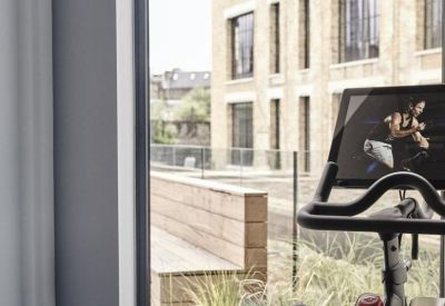 Bright fitness area with exercise bikes overlooking a brick building facade.