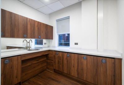 Modern kitchenette with dark wood cabinetry, white countertops, and integrated appliances.