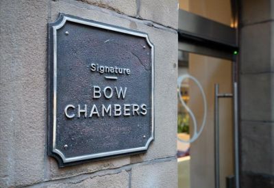 Classic dark metal building plaque mounted on a light stone wall.