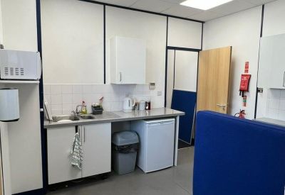 Communal kitchen area with white cabinets, blue privacy screens, and recessed ceiling lights.