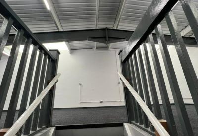 Close-up of a dark grey staircase with white handrails leading to an upper mezzanine level.
