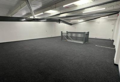 Wide view of a large, carpeted upper-floor office space featuring exposed ceiling beams and bright lighting.