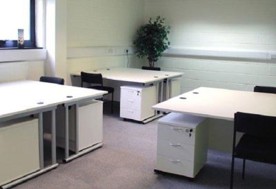 Simple office suite with three white desks, black chairs, and small indoor plants.