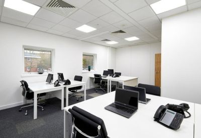 Open-plan office space featuring white desks, black chairs, and natural light.