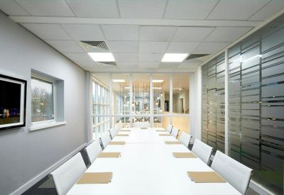 Bright boardroom with a long white table and frosted glass partitions.