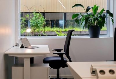 Modern communal kitchen and dining area with light wood floors and industrial-style lighting.