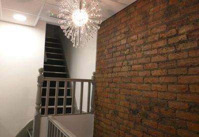 Hallway featuring a rustic exposed brick feature wall and a decorative crystal chandelier.