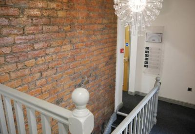 Upper landing area showing the exposed brick wall and white wooden bannisters.