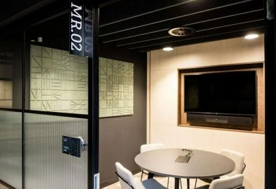 Small private meeting room with a round table, four chairs, and a wall-mounted television.