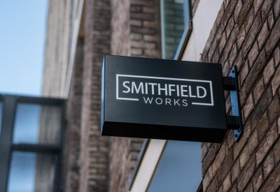Black rectangular hanging sign for Smithfield Works on a traditional brick building exterior.