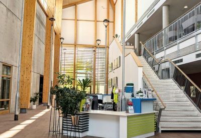 Bright, high-ceilinged reception area with a white desk and large windows.